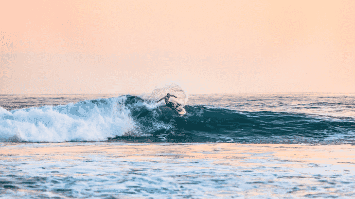 man-surfing-sans-wetsuit-blue-water-sunset