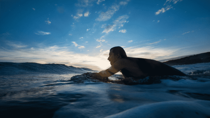 man-paddling-out-for-surf-sunset