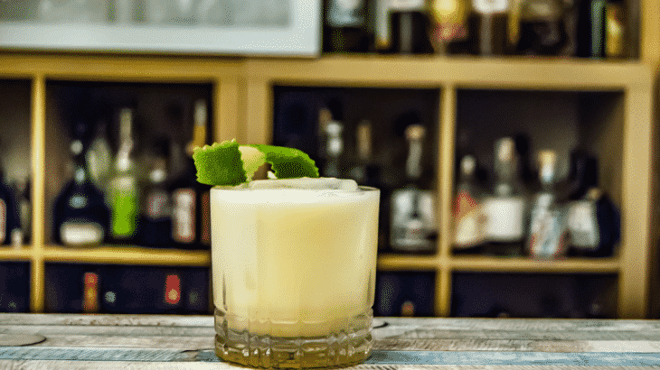 yellow-cocktail-with-lime-sitting-on-bar