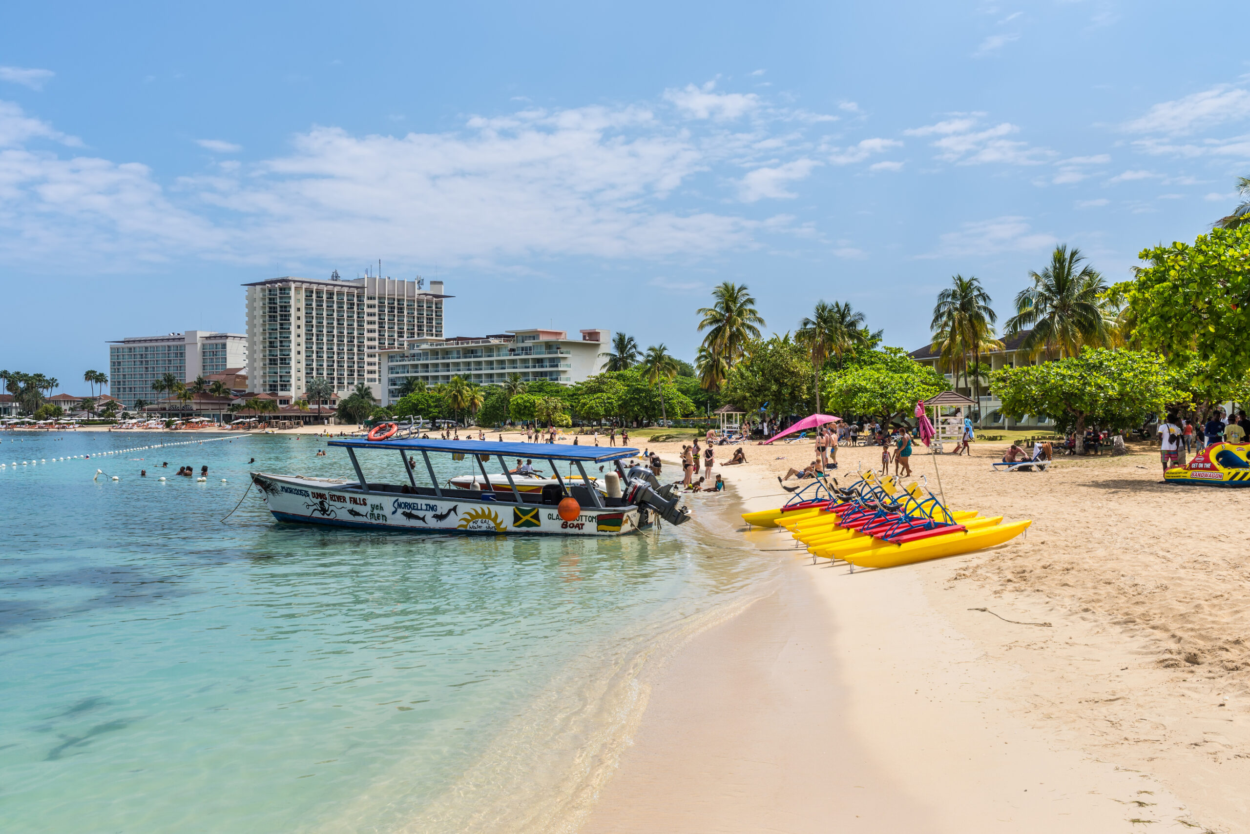 Motor boat and paddle boats pedalos on sandy Ocho Rios Bay Beach in Ocho Rios, Jamaica.