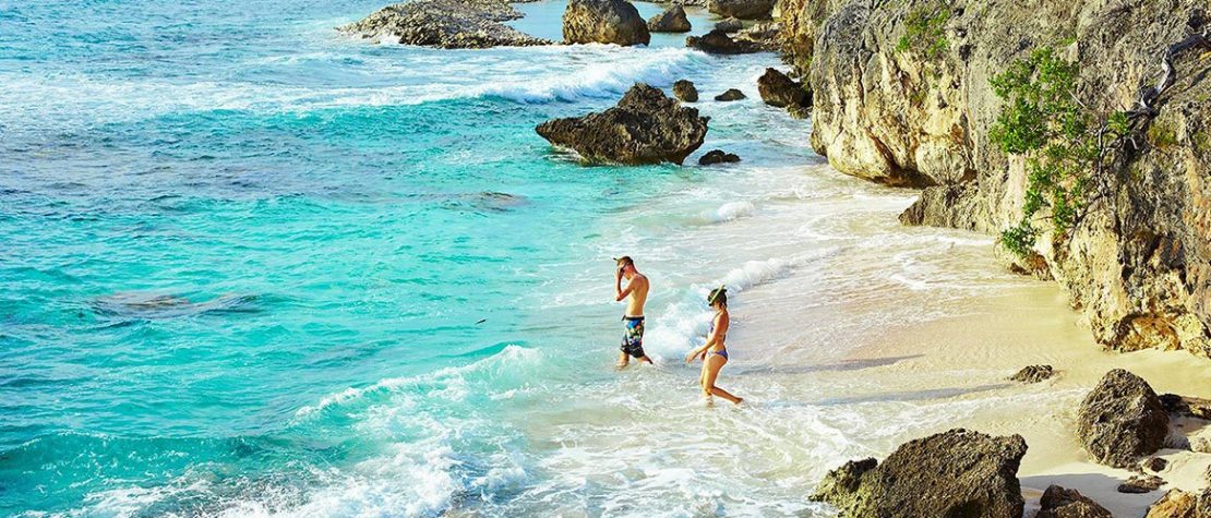 beach-snorkelers-turquoise-ocean-cliffs