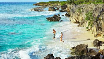 beach-snorkelers-turquoise-ocean-cliffs