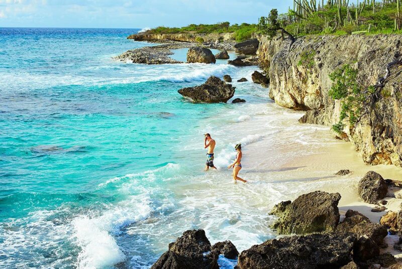 beach-snorkelers-turquoise-ocean-cliffs
