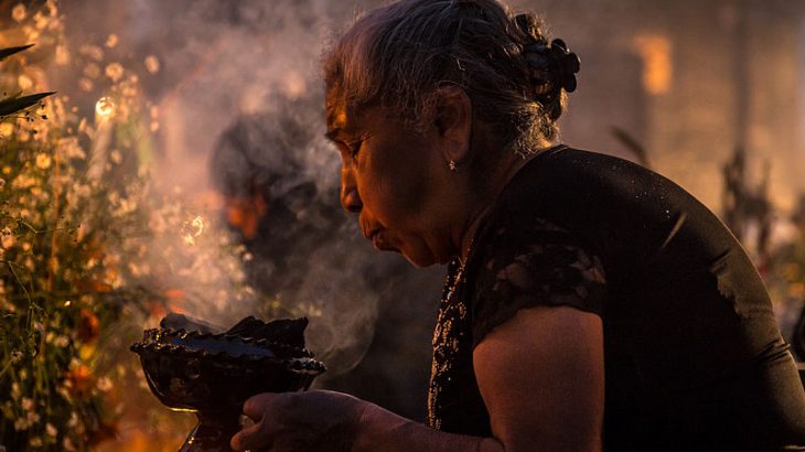 older-woman-blowing-on-copal-incense-day-of-the-dead-mexico