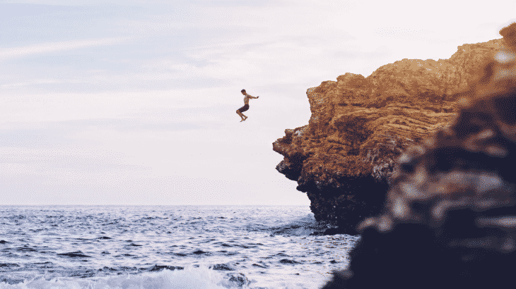 man-jumping-into-ocean-off-cliff