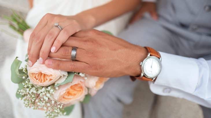 couples-hands-on-bouquet-wedding-rings-watch