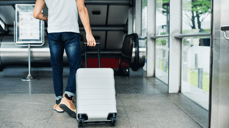 man-walking-to-escalator-suitcase