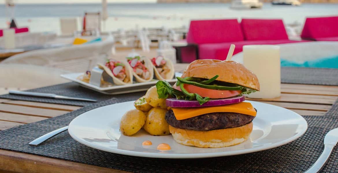 burger-on-white-plate-tacos-next-beach-background