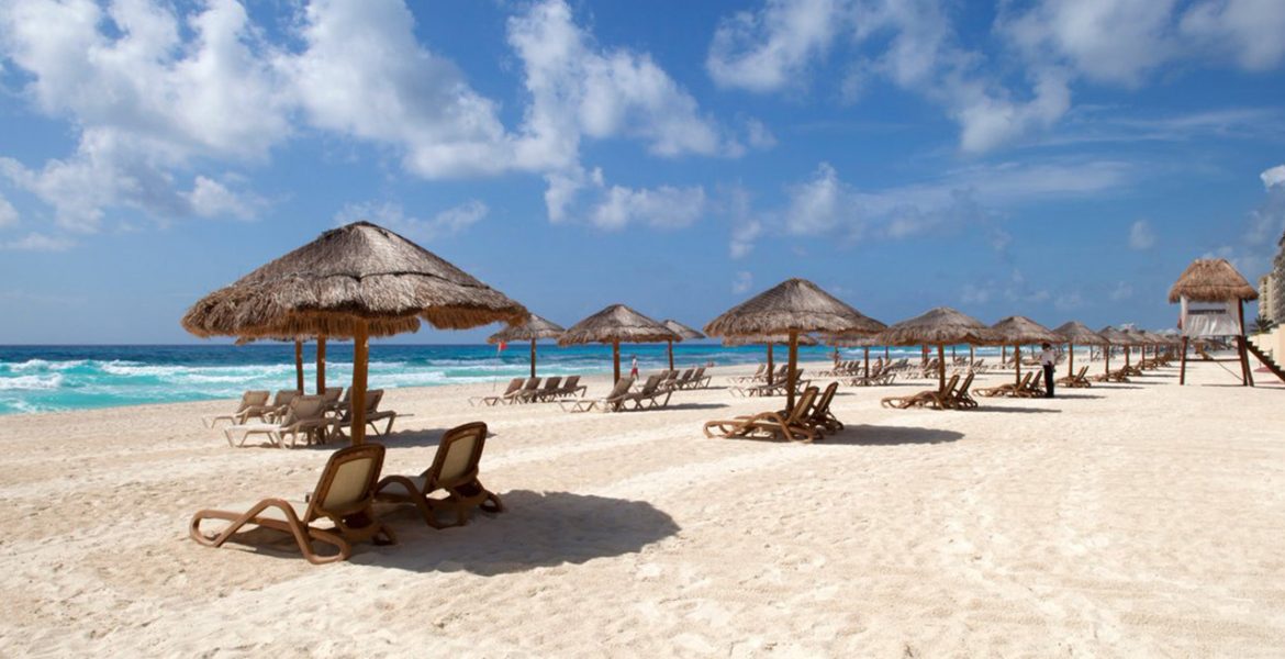 white-sand-beach-tiki-style-umbrellas-over-loungers