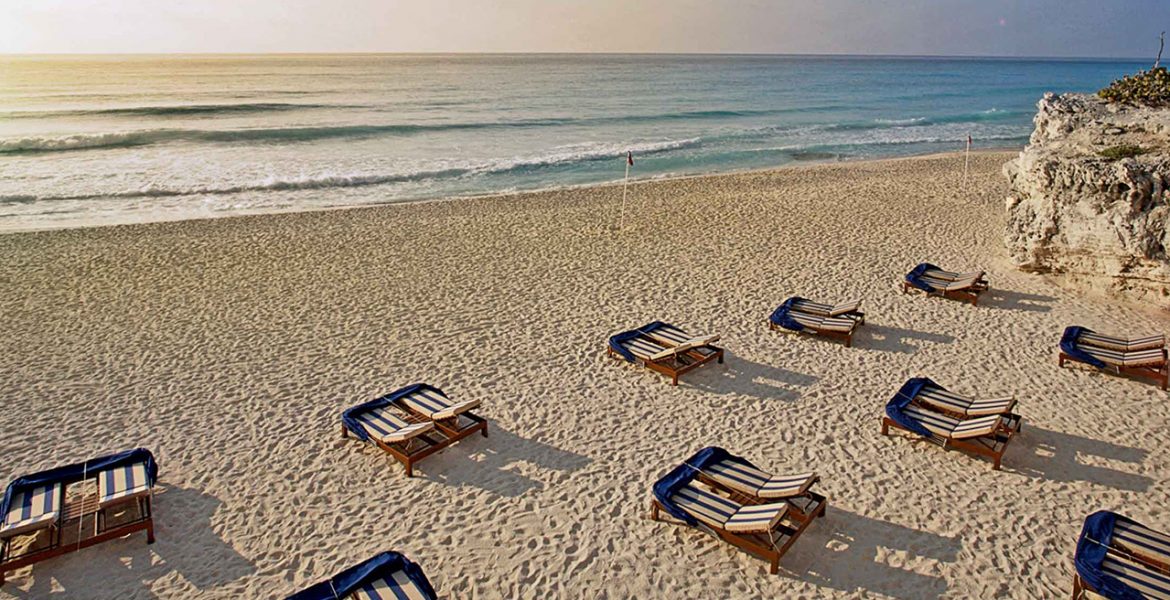 beach-loungers-white-sand-ocean-sunset