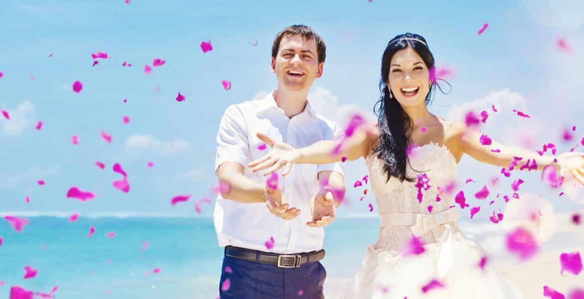 bride-groom-on-beach-throwing-pink-flower-petals