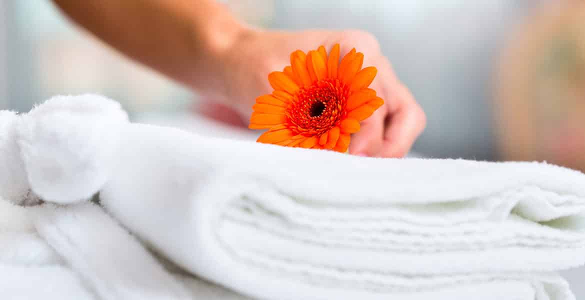 hand-holding-orange-flower-on-white-towel