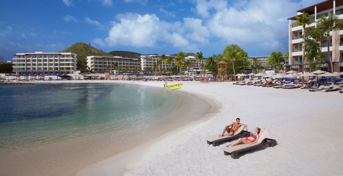 cresent-shaped-beach-white-sand-couple-laying-blue-water