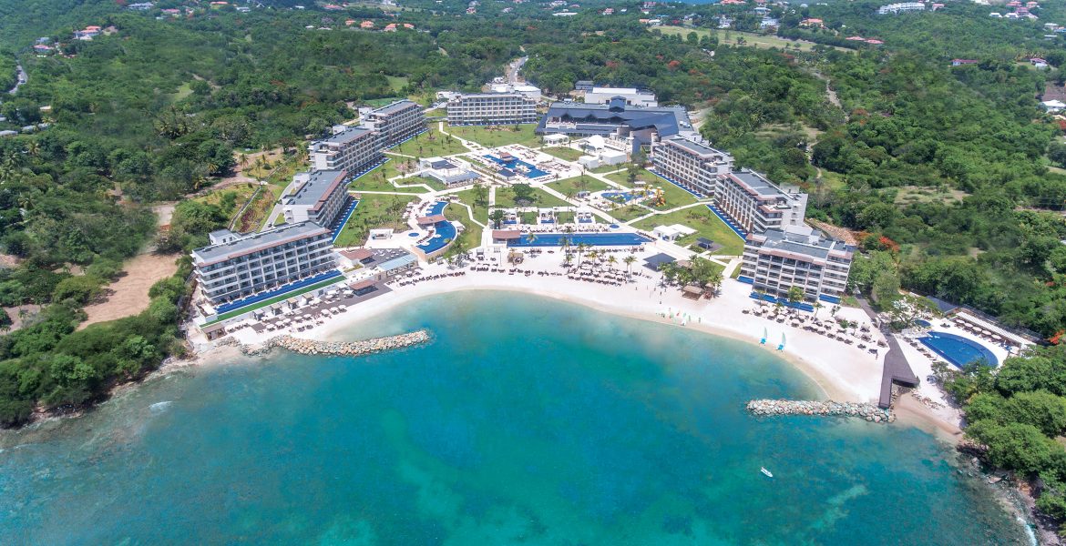 aerial-view-blue-ocean-cove-white-resort-surrounded-by-green-jungle