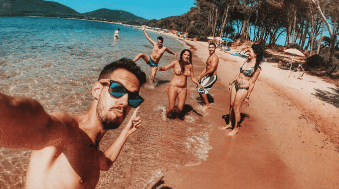 guy-taking-selfie-of-him-and-friends-on-golden-sand-beach