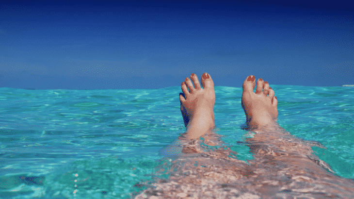 person-floating-clear-blue-water-only-legs-feet-pictured