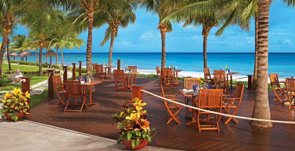 beachfront-dining-wood-tables-blue-ocean-behind