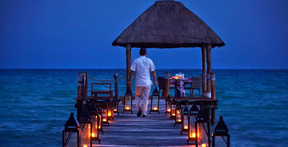 man-walking-to-end-of-pier-lit-candles