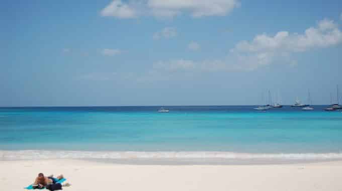 man-laying-on-beach-barbados-turquoise-ocean