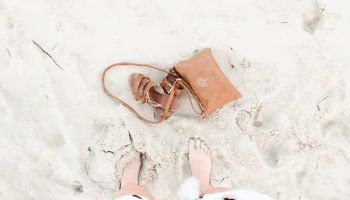 view-womans-feet-in-sand-brown-sandals-purse