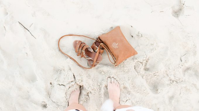 view-womans-feet-in-sand-brown-sandals-purse