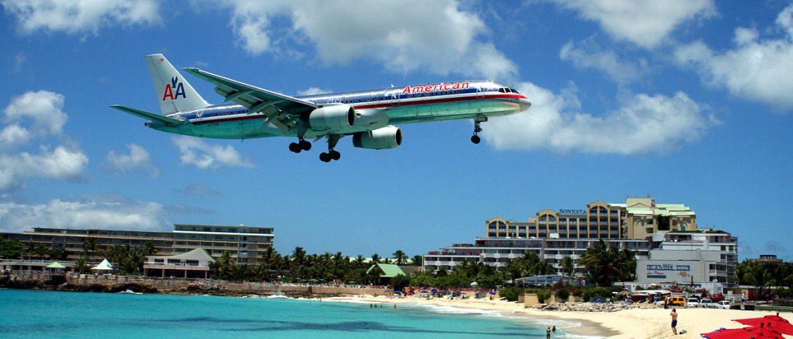 plane-flying-low-over-beach-people-watching