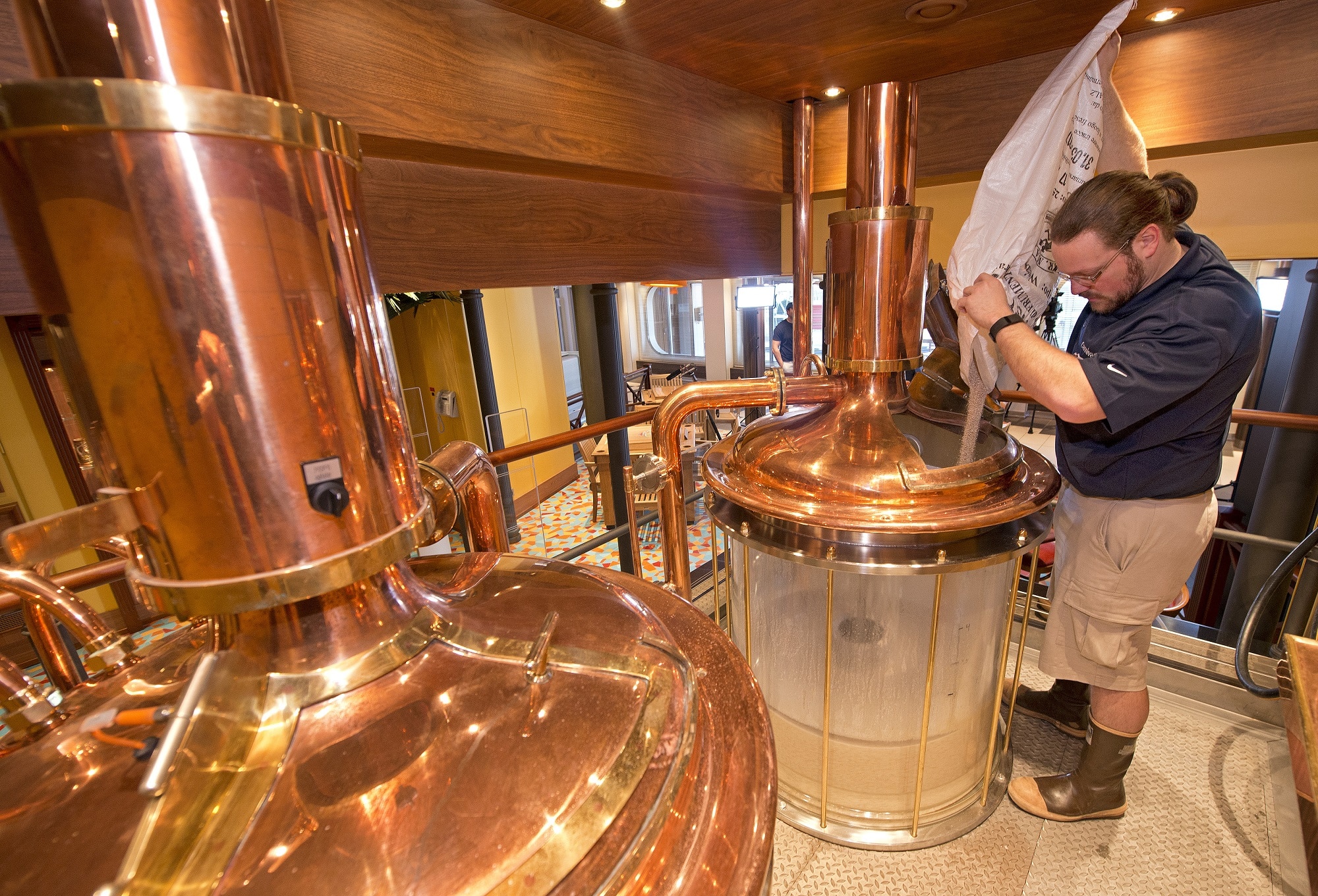 Carnival Vista Brewmaster Colin Presby pours malt into a mash tun located in the RedFrog Pub's brewery house onboard the Carnival Vista.