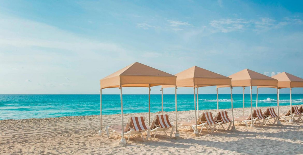 white-sand-beach-lounge-chairs-tan-tents-blue-ocean