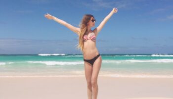 woman-standing-beach-raising-arms