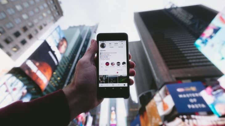 hand-holding-phone-up-city-buildings-backdrop