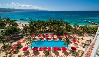 The main pool at the S Hotel Montego Bay with sunbeds and umbrelllas and the beach beyond