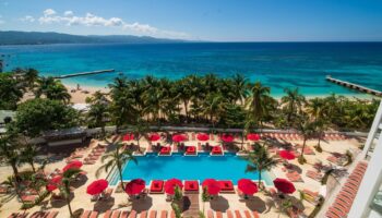 The main pool at the S Hotel Montego Bay with sunbeds and umbrelllas and the beach beyond