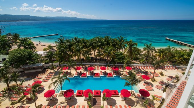 The main pool at the S Hotel Montego Bay with sunbeds and umbrelllas and the beach beyond