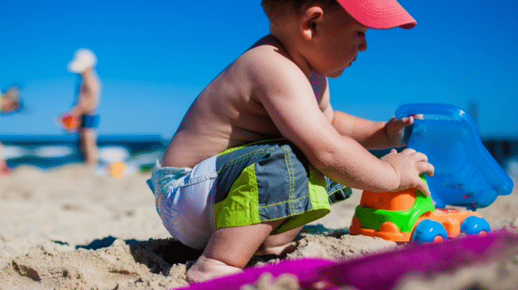 boy-toddler-playing-in-sand-colorful-tools