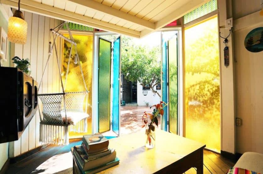 A hammock and coffee table with books await a solo traveler through the open door of The Glass Cottage at the Dreamcatcher Hotel Puerto Rico