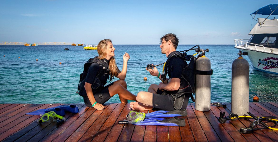 couple-going-scuba-diving-sitting-on-dock