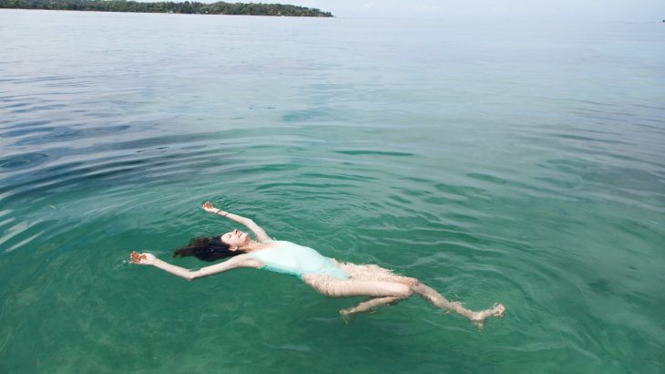 woman-blue-bathing-suit-floating-turquoise-water-smiling