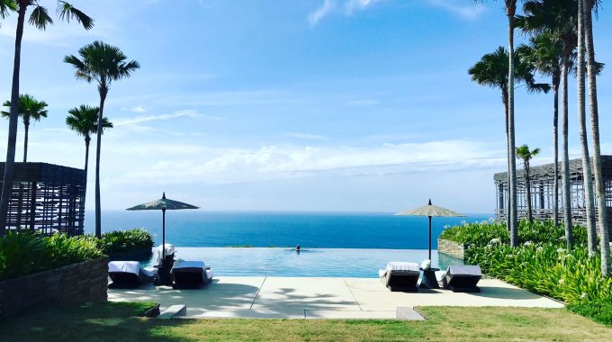 view-of-resort-infinity-pool-overlooking-ocean-palm-trees-buildings