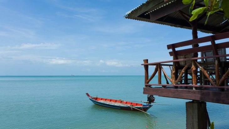 small-boat-floating-in-water-next-to-cottage