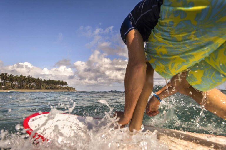 close-up-man-surfing-feet-beach-clouds-in-distance