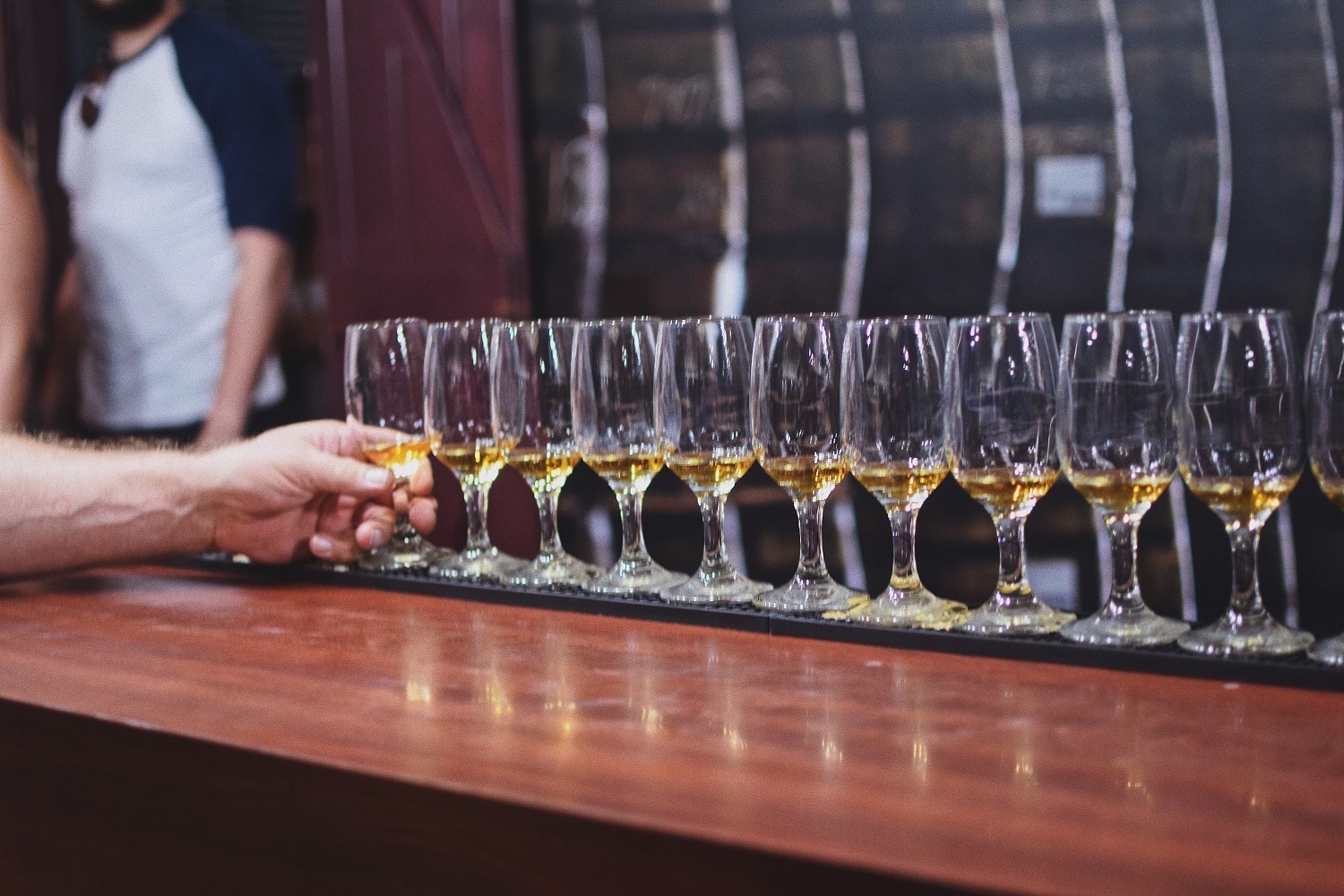 Lineup of rum tasting glasses as someone's hand selects one at a rum tour