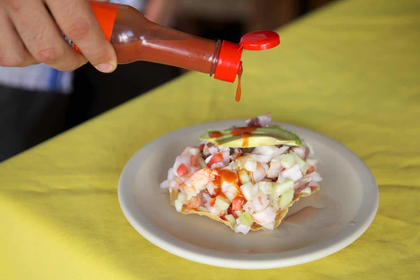 Hot sauce being poured on a fresh taco on a Vallarta Food Tour