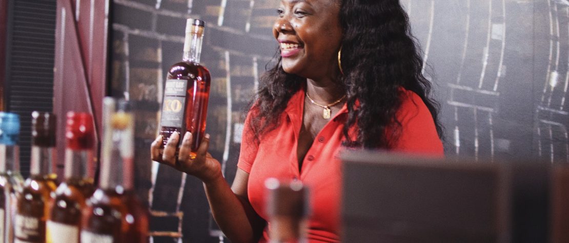 A woman holds a bottle of rum on part of the rum tour at Mount Gay - hosted with a smile