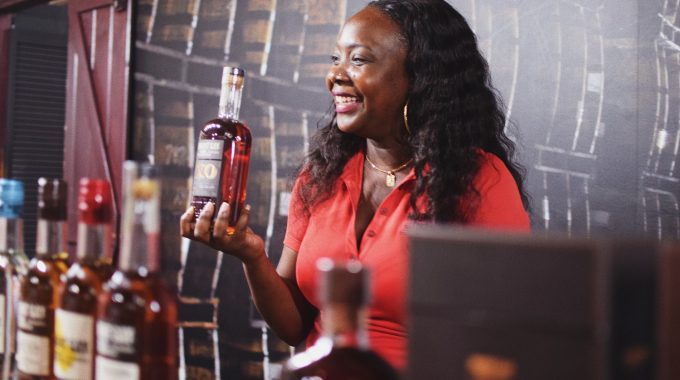 A woman holds a bottle of rum on part of the rum tour at Mount Gay - hosted with a smile