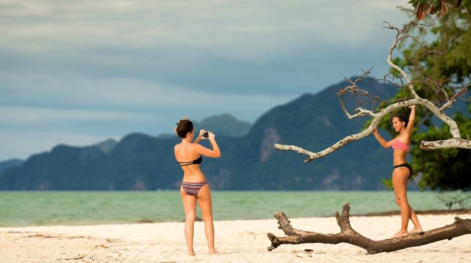 Girls taking photos on beach in bikinis