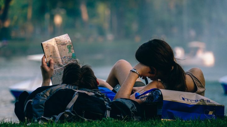 man-woman-laying-grass-researching-vacation