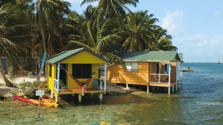 Two yellow overwater bungalows side by side with hammocks