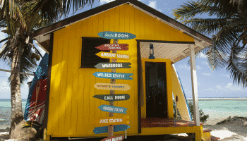 yellow bungalow on the ocean with signs pointing all directions