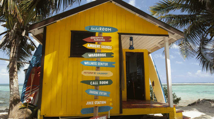 yellow bungalow on the ocean with signs pointing all directions