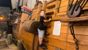 Little boy wearing black shirt playing on pirate ship at the Pirates of Nassau Museum